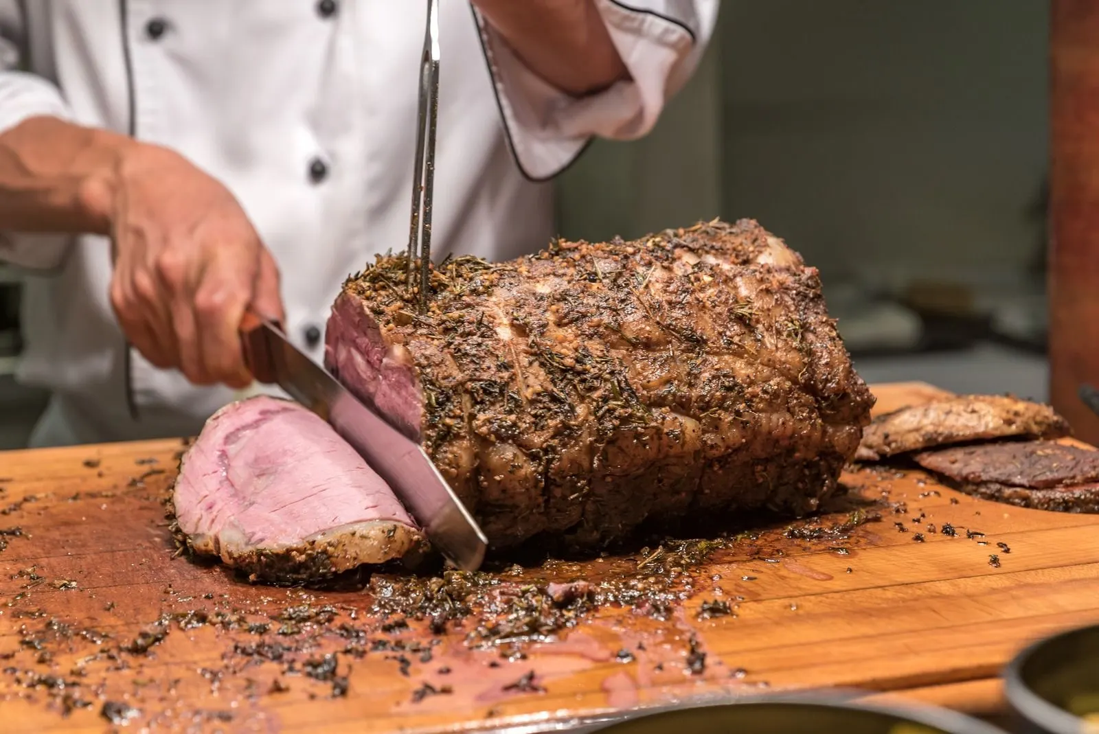 A whole beef roast being carved into slices on a board