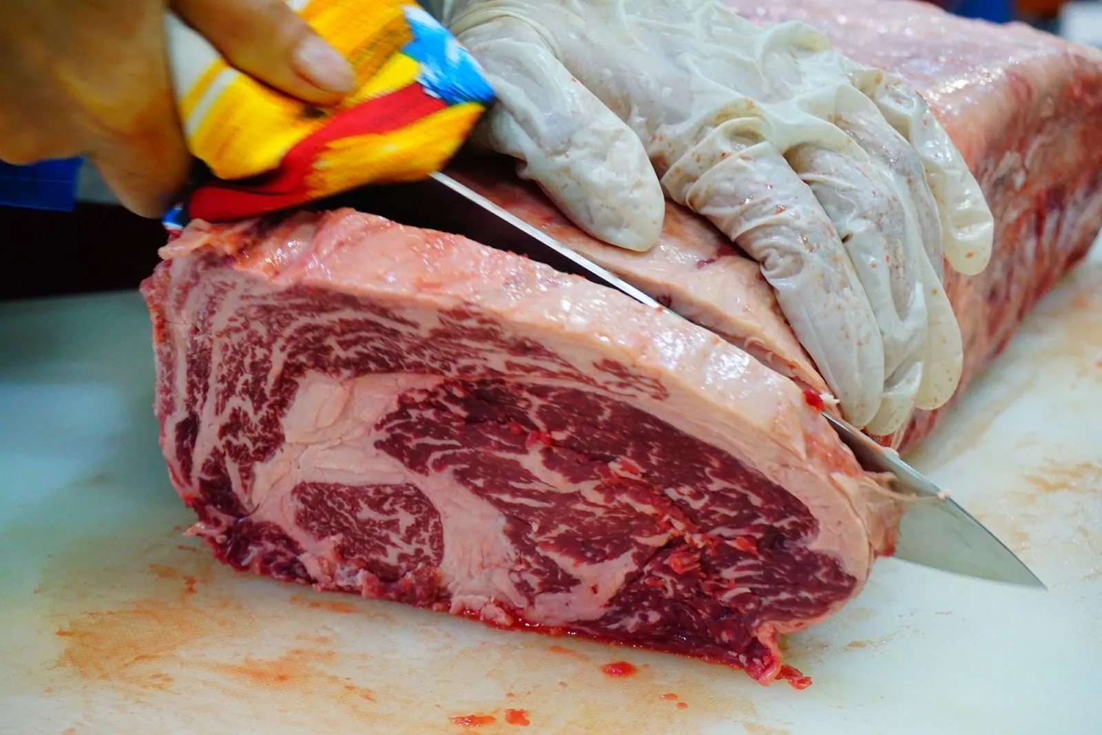 A whole cube roll on a butcher block, part-way through being cut into steaks, the marbling visible across the face
