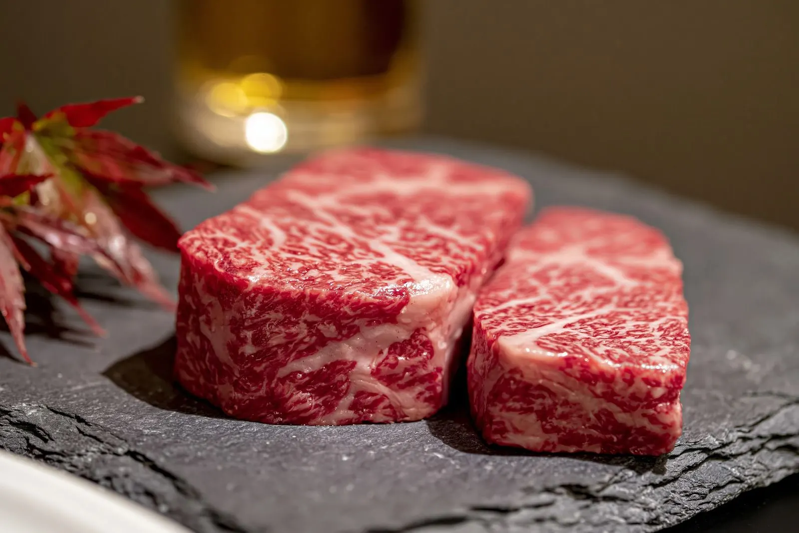 Two thick raw marbled steaks on dark slate